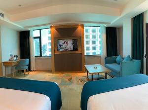 a hotel room with two beds and a couch and a tv at SENNA SUNSHINE INTERNATIONAL HOTEL in Sihanoukville
