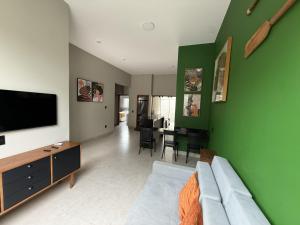 a living room with a couch and a green wall at Casas Pantanal - Privacidade e conforto no centro de Bonito in Bonito