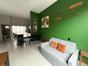 a living room with a white couch and a green wall at Casas Pantanal - Privacidade e conforto no centro de Bonito in Bonito