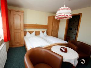a bedroom with a bed and a chair and a table at Gästehaus Klingele in Hinterzarten