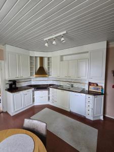 a large kitchen with white cabinets and a table at Linnansalmi Lakeside Villa with Sauna in Savonlinna +5 photos