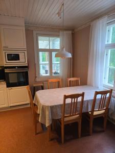 a dining room table with chairs and a table and a kitchen at Linnansalmi Lakeside Villa with Sauna in Savonlinna