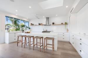 a kitchen with white cabinets and bar stools at Lucy - Noosa - Noosaville in Noosaville