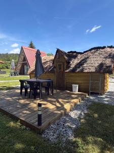 a wooden deck with a table and an umbrella at Loray des Bois - Cabane - Tipi - Cottage in Loray