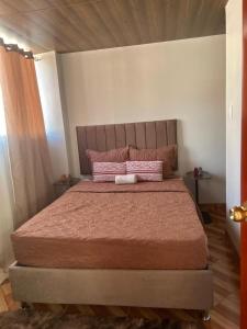 a bedroom with a large bed with pink pillows at Wiracocha Apartments #4 in Pisac +9 photos