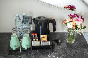 a counter with a coffee maker and a vase of flowers at Hotel Clover Patong Phuket in Patong Beach