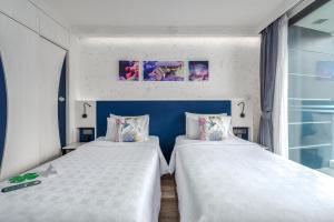 two beds sitting next to each other in a room at Hotel Clover Patong Phuket in Patong Beach