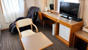 a room with a desk with a television and a chair at Center Hotel Mihara in Mihara