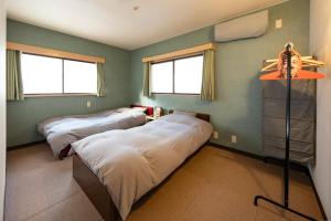 a room with three beds and two windows at TANIGAWA GOODY Lodge in Minakami