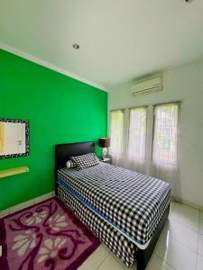 a green bedroom with a bed and a green wall at Arcovella House in Cikarang