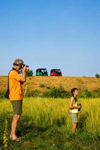 a man taking a picture of a woman in a field at Richards Cabanas in Tissamaharama