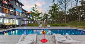 a hotel with a pool and chairs and a table at Taean janggog pension in Taean