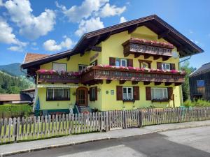 a yellow house with a fence in front of it at Haus zur Linde in Wagrain