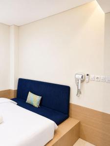 a room with a bed and a blue couch at Una Hotel in Mantaak