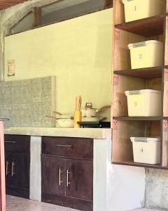 a kitchen with a counter and shelves with pots and pans at Patrick's on the Beach Resort in General Luna