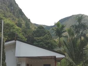 a white building with a mountain in the background at Duleni villa in Haldummulla