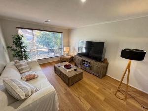 a living room with a couch and a flat screen tv at Canberra Stylish Escape in Harrison