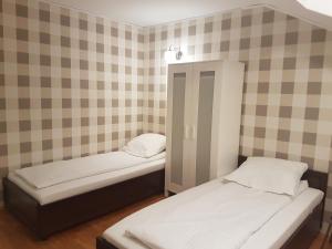 two twin beds in a room with checkered walls at Duszka Hostel in Warsaw