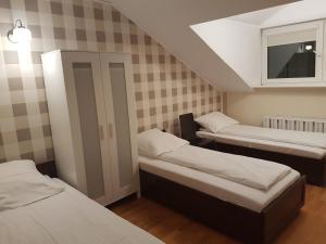 ワルシャワにあるDuszka Hostelのベッド3台と窓が備わる小さな客室です。