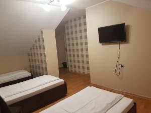 a room with two beds and a tv on the wall at Duszka Hostel in Warsaw