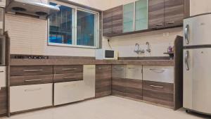a kitchen with wooden cabinets and a stainless steel refrigerator at Tejas 4 Bhk Villa in Pune