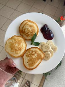 a white plate with pancakes and bananas and jam at Green House in Cholpon-Ata