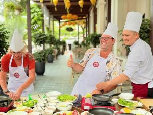 a group of people standing in a kitchen preparing food at Little Residence - A Boutique Hotel & Spa in Hoi An