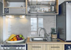 a kitchen with a bowl of fruit on a sink at Thalassa Beach Kavala in Paleo Tsifliki +53 photos