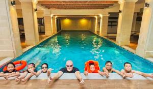 a group of people laying in a swimming pool at Little Residence - A Boutique Hotel & Spa in Hoi An