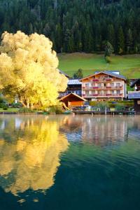 un reflet d'un bâtiment dans une masse d'eau dans l'établissement Draxl-Hof Ferienwohnungen, à Weissensee