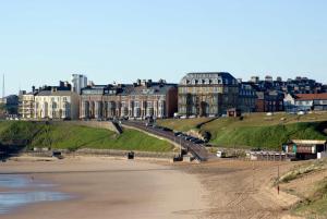 a large building on a hill next to a beach at Tynemouth Grand Hotel in Tynemouth