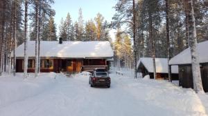 une voiture garée dans la neige devant une cabine dans l'établissement Kuulapää Chalet, à Äkäslompolo