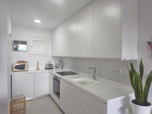 a white kitchen with white cabinets and a sink at Calma Bungalow 54b en Urbanización La Roca in Torremolinos