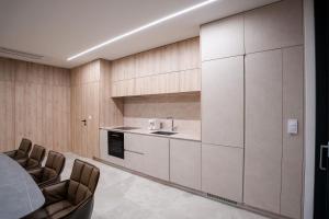 a kitchen with white cabinets and chairs in a room at Villa FUX Eternity 3 in Ždrelac