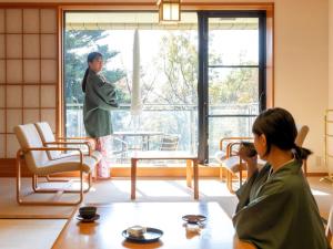 a woman standing in a room looking out the window at Izukogen Hotel Itsutsuboshi in Ito