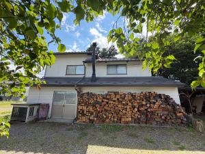 a pile of fire wood on the side of a house at 一棟貸しの宿 餓鬼大将と別館トキワ荘 in Omachi