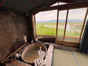 a bath tub in a room with a window at 一棟貸しの宿 餓鬼大将と別館トキワ荘 in Omachi