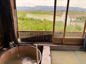 a tub filled with water next to a window at 一棟貸しの宿 餓鬼大将と別館トキワ荘 in Omachi