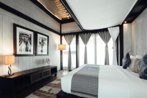 a bedroom with a large bed and some windows at Suarga Padang Padang - CHSE Certified in Uluwatu