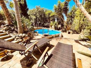 a patio with chairs and a swimming pool with palm trees at Casa Mora, privater pool, Meerblick, toller Garten in Torrox