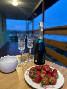 a bottle of wine next to two glasses and a plate of strawberries at Зелений двір in Vapnyarka