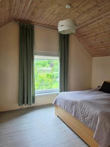 a bedroom with a bed and a large window at Cosy Hideaway Guest House in Dovilai