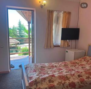 a bedroom with a bed and a tv and a window at Green House in Cholpon-Ata +25 photos
