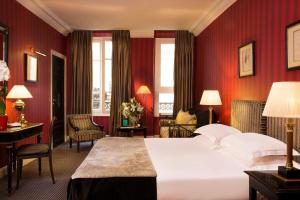 a hotel room with a bed, chair, table and lamps at Villa d'Estrées in Paris