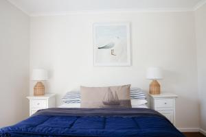 a bedroom with a bed with blue sheets and two lamps at 'The Perch' - Central location in Robe, park your car and walk to everything in Robe