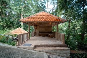 a wooden boardwalk with a pavilion in a forest at River Temple Villa in Ubud