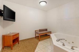 a bathroom with a tub and a tv and a chair at Comfort Suites Longmont in Longmont +45 photos