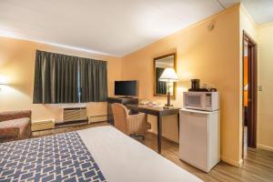 a hotel room with a bed and a desk with a microwave at Econo Lodge Inn & Suites Windsor Locks Bradley Airport in Windsor Locks