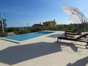 a swimming pool with two lounge chairs and an umbrella at Apartment Tireli in Labin