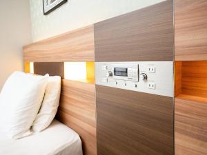 a hotel room with a bed and a wall with a control panel at Comfort Hotel ERA Tokyo Higashi Kanda in Tokyo